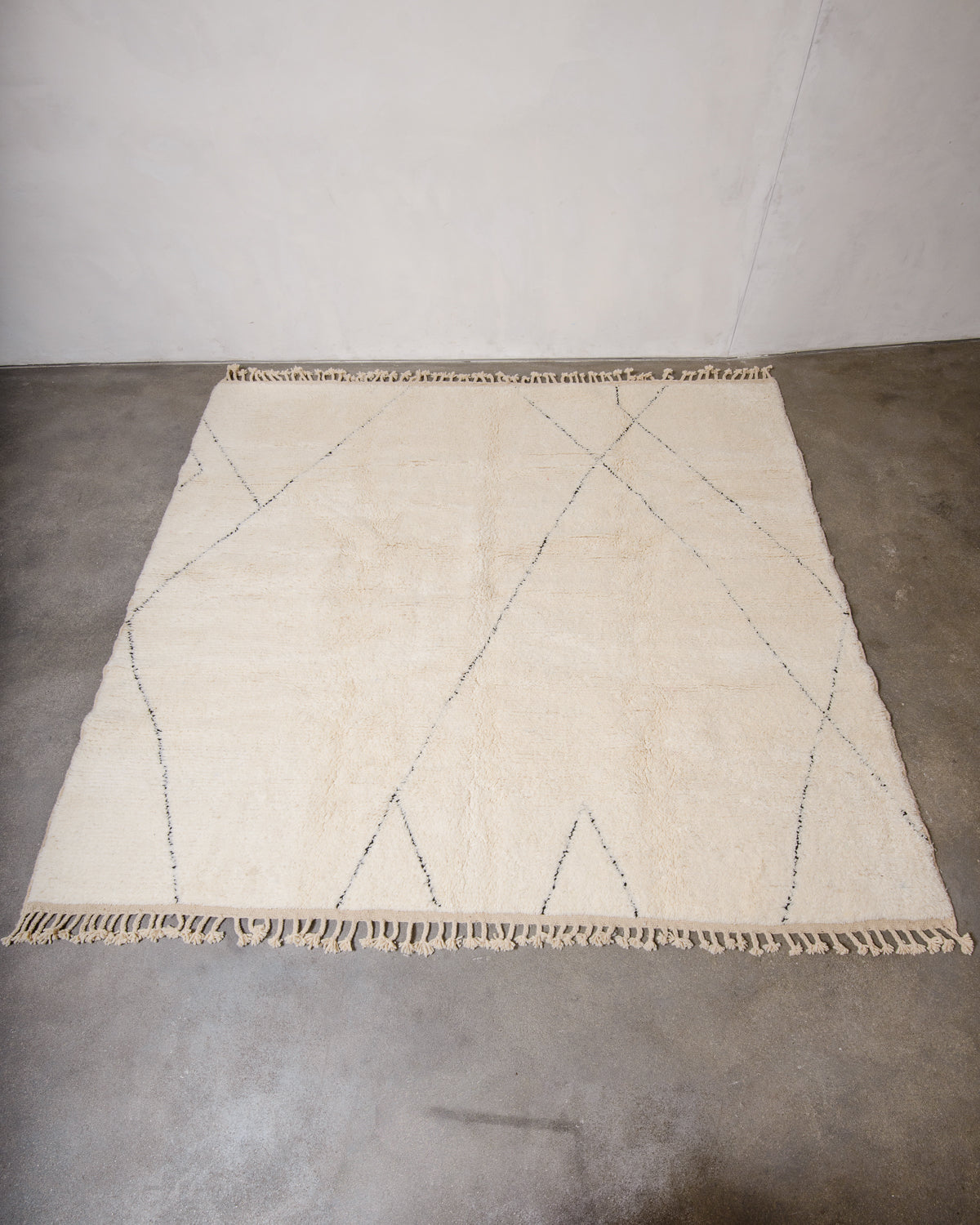 Berberlin Beniourain rug with minimal black line design laying flat on concrete floor.